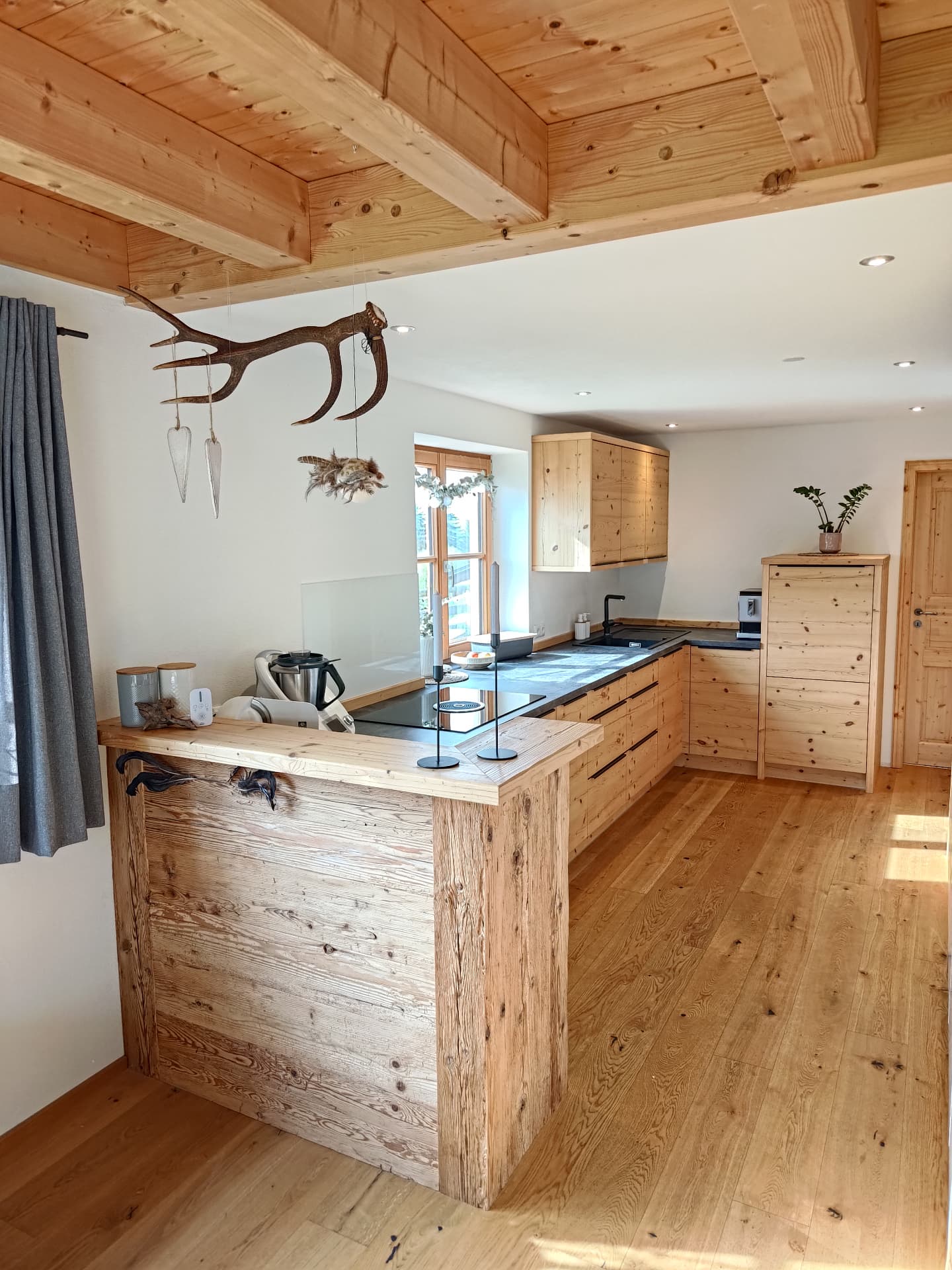 Küche mit Tresen aus Altholz und Holzdecke